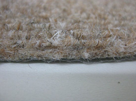 Dichtbij zicht op de lusjesstructuur van een beige trapmat.
