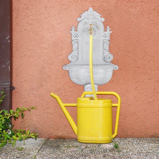 Gouden kraan van een witte muurfontein vult een gele gieter.