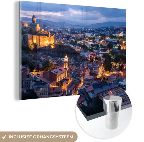 MuchoWow® Glasschilderij 120x80 cm - Schilderij acrylglas - Overzicht over de stad Tbilisi in de avond - Foto op glas - Schilderijen