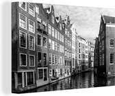 Canvas schilderij 180x120 cm - Wanddecoratie Grachtenpanden langs het kanaal in Amsterdam - zwart wit - Muurdecoratie woonkamer - Slaapkamer decoratie - Kamer accessoires - Schilderijen