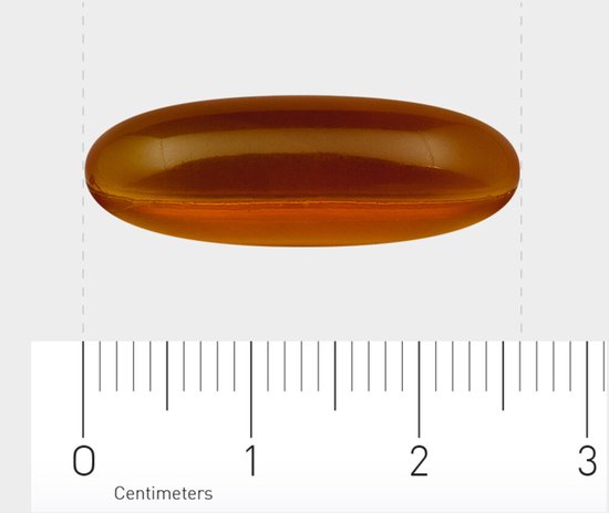 Gouden, ovale softgel met een transparante capsule, gemeten op een centimeter liniaal.