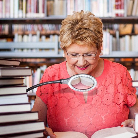 Vrouw leest boek met loeplamp met LED-ring