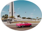WallClassics - PVC Schuimplaat Ovaal - Roze Auto bij Gebouw in Cuba - 28x21 cm Foto op Ovaal (Met Ophangsysteem)