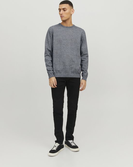 Man met een donkerblauwe gebreide trui met ronde hals en zwarte jeans.