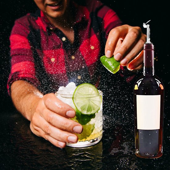 Barman maakt cocktail met munt en schijfjes limoen. Fles met zilverkleurige schenktuit ernaast. Spetters in de lucht.