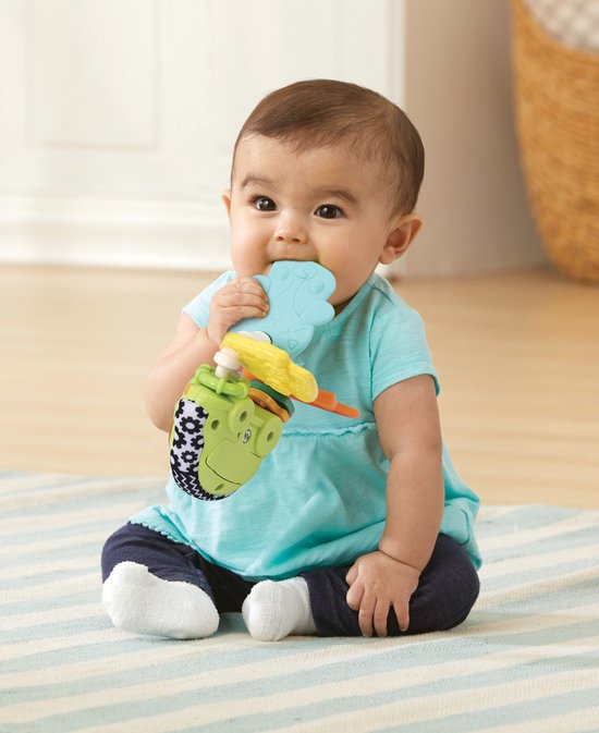 Baby in blauw shirtje bijt op lichtblauwe en gele onderdelen van de VTech rammelsleutel.