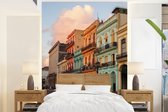 Behang - Fotobehang Oude auto's voor de kleurrijke gebouwen van Cuba - Breedte 195 cm x hoogte 260 cm
