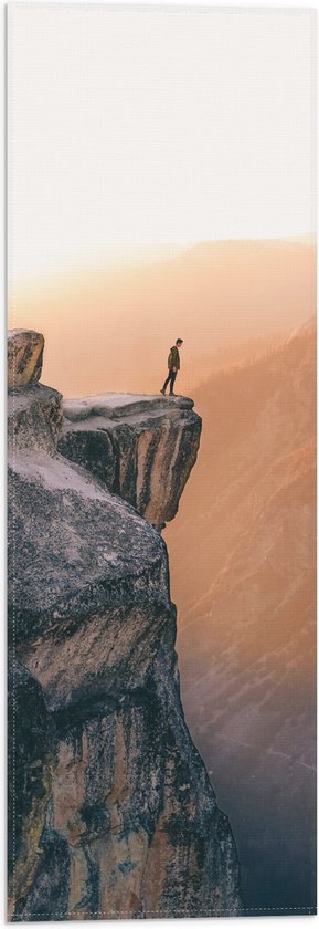 WallClassics - Vlag - Man aan de Rand van Hoge Cliff met Zonlicht - 20x60 cm Foto op Polyester Vlag