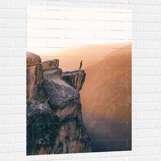 WallClassics - Muursticker - Man aan de Rand van Hoge Cliff met Zonlicht - 80x120 cm Foto op Muursticker
