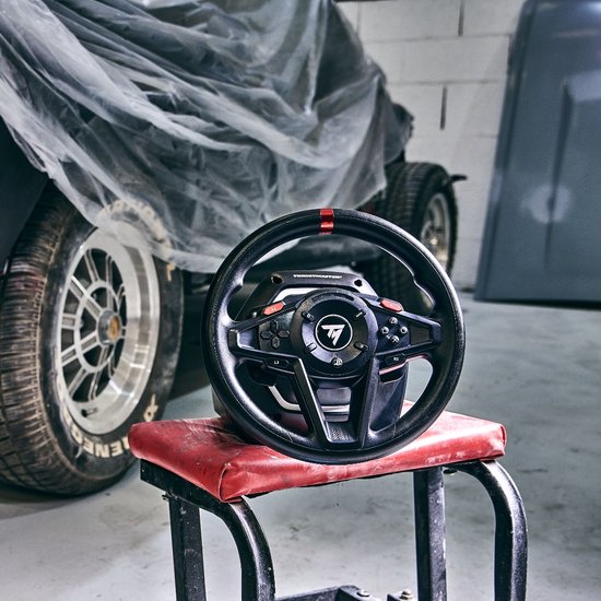 Thrustmaster racestuur op een rode kruk, met een auto in de achtergrond.