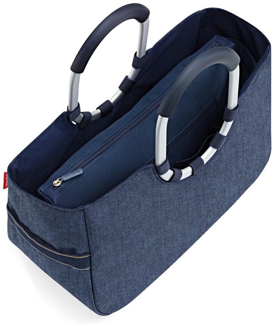 Donkerblauwe shopper met spijkerstof textuur, open met toilettas erin.