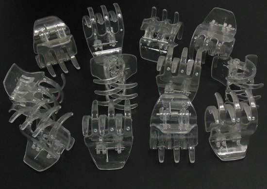 Een set van acht transparante haarclips in de vorm van een hand met vier vingers.