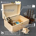 Open houten kist met scharnierend deksel, met gouden slot en versierd met schelpen en een miniatuurschip.