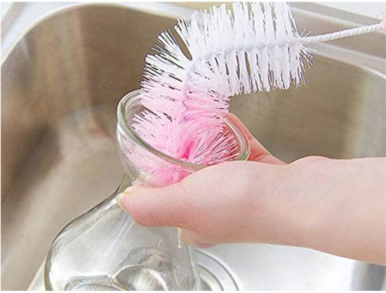 Een roze en witte flesborstel reinigt de binnenkant van een glazen fles.