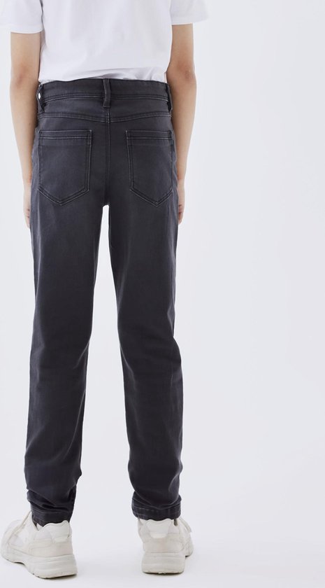 Jongen met grijze slim fit spijkerbroek, gezien vanaf de achterkant.