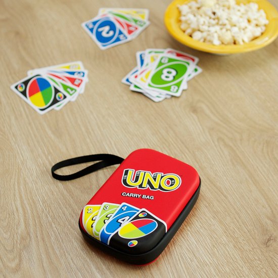 Rode UNO-draagtas met kaartafbeeldingen, op een houten ondergrond met UNO-kaarten en popcorn.