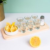 Plateau en bois avec six verres à shot, quartiers de citron, salière et citron.