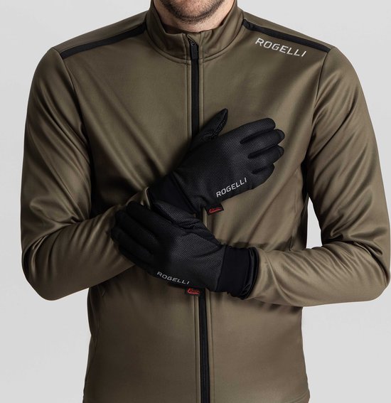 Man in groen jack met zwarte Rogelli fietshandschoenen, de handen gekruist voor de borst.