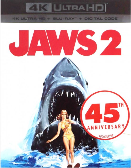 De iconische poster van Jaws 2, met een gevaarlijke haai met opengesperde bek en een vrouw in een bikini die door de golven peddelt.