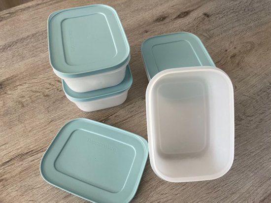 Quatre boîtes de congélation Tupperware bleu clair, dont deux empilées et deux séparées avec leurs couvercles à côté.