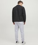Man, achterkant, met lichtgrijze joggingbroek en donkere jas.