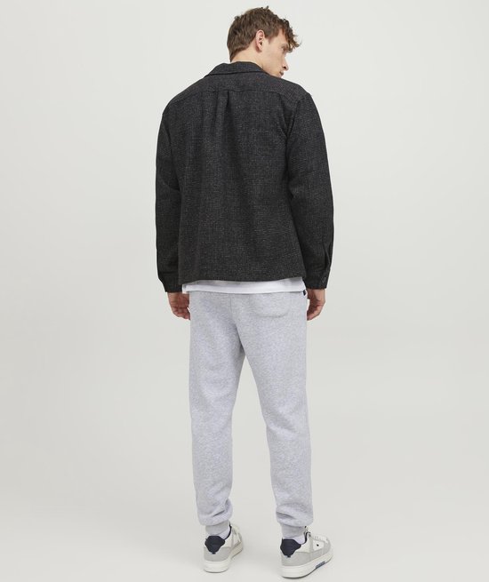 Man, achterkant, met lichtgrijze joggingbroek en donkere jas.