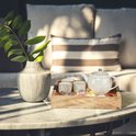 Wit theepot en kopjes met fruit en bloemen op een houten dienblad.