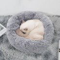Witte kat slaapt in een ronde, zachte, grijze mand.
