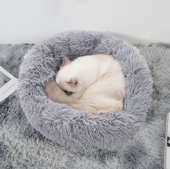 Witte kat slaapt in een ronde, zachte, grijze mand.