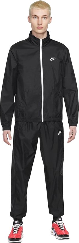 Man draagt een zwart Nike trainingspak met witte rits en Swoosh logo.