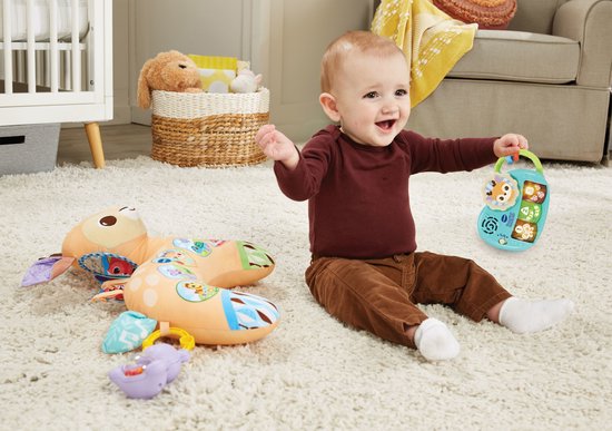 Baby met het VTech Tummy Time Knuffelhertje en losse speelgoed piano. De baby draagt een bordeaux shirt en bruine broek.
