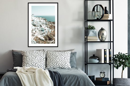 Maison blanche avec mer bleue en arrière-plan, dans un cadre noir.