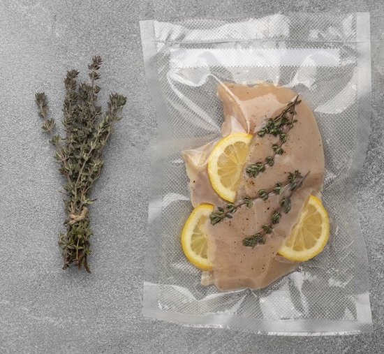 Kipfilet, vacuüm verpakt met citroen en tijm, naast een bosje tijm.