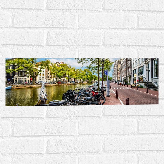 Muursticker - Rij Fiets Geparkeerd langs de Gracht in Amsterdam - 60x20 cm Foto op Muursticker