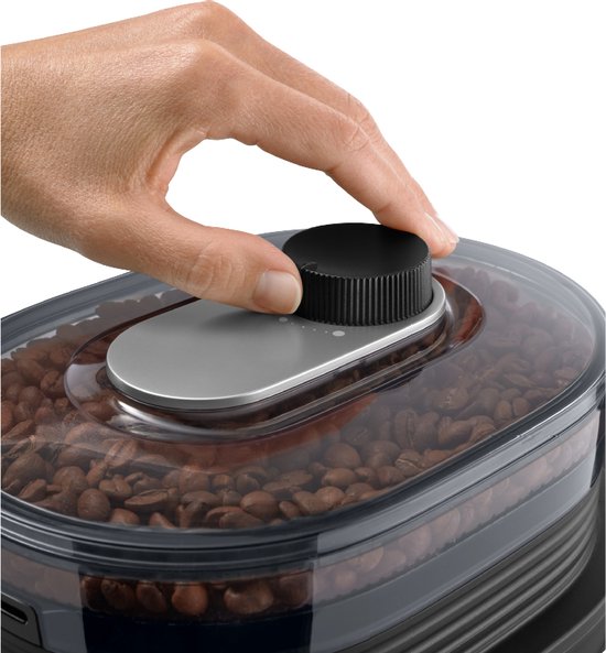 Hand draait aan zwarte knop op koffiezetapparaat gevuld met koffiebonen.