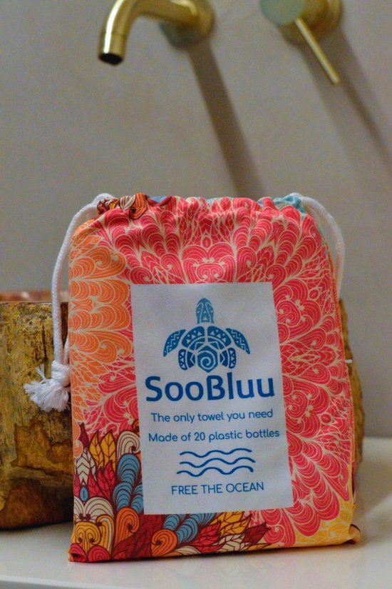 Een opgevouwen strandhanddoek in een tasje met felgekleurde mandala print. Tekst op het label: 'SooBluu', 'Free the ocean'.