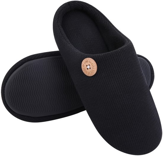 Zwarte pantoffels met beige knoop, geribbelde buitenkant en anti-slip zool met golfpatroon.