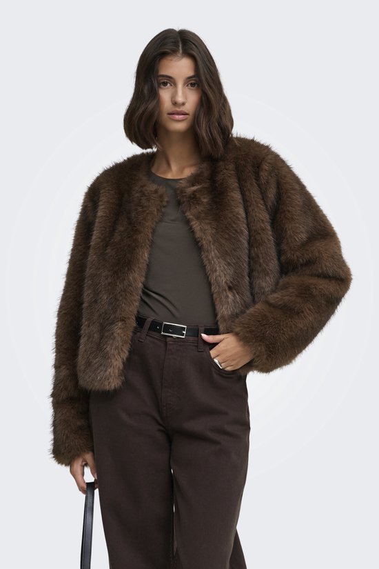 Model draagt een bruin imitatiebont jack, gecombineerd met een donkerbruine broek en zwarte riem.