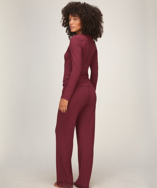 Model in bordeauxrode pyjamaset, zijaanzicht, met kanten detail aan de zoom van de broek.