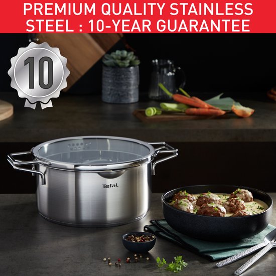 Tefal pannenset van RVS met glazen deksel, naast een kom met gehaktballetjes in saus.