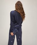 Achterkant model in donkerblauwe velours pyjamaset met strikje print op de broek.