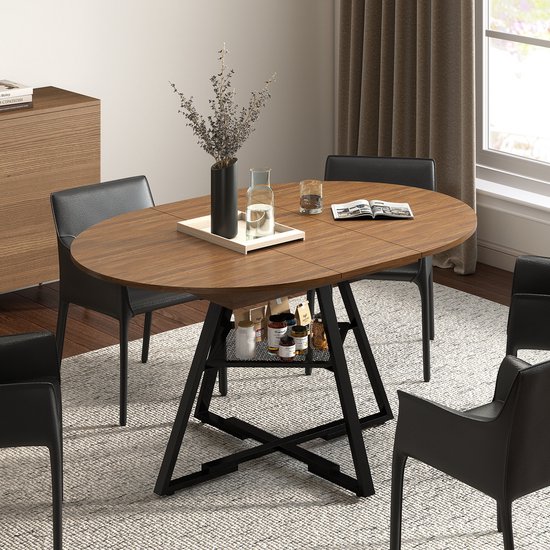 Ovale walnootkleurige eettafel met zwart metalen kruisframe, opbergplank onder het tafelblad. Vier zwarte stoelen.