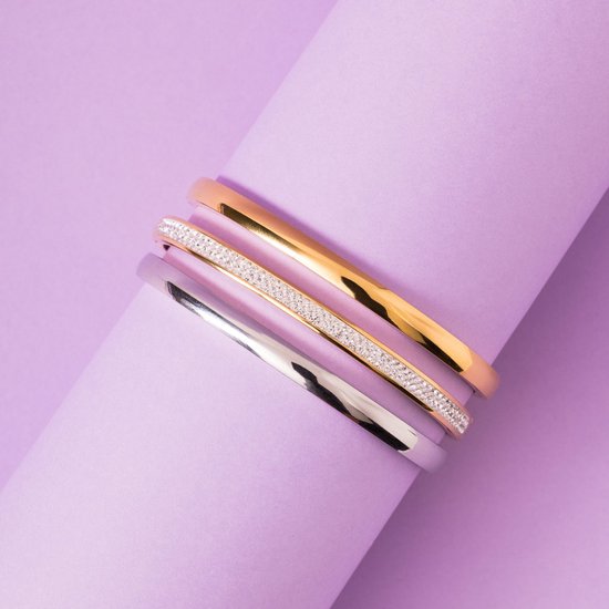 Drie gestapelde armbanden: één goudkleurige, één zilverkleurige en één met een rij kleine zirkonia steentjes.