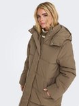 Een vrouw met blond haar draagt een lange, bruine pufferjas met capuchon.