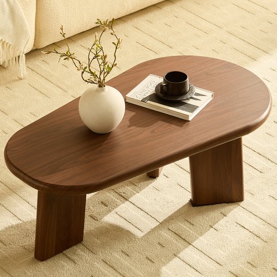 Bruine organische salontafel met vaas en boek op een beige tapijt.