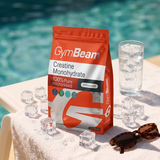 Een GymBeam Creatine Monohydraat zak, niet-gearomatiseerd, op een handdoek bij een zwembad met ijsblokjes.
