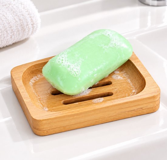 Porte-savon en bois avec un savon vert clair et moussant dessus.
