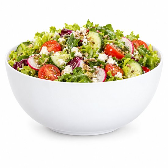 Grote, effen witte kom gevuld met een verse salade op een witte achtergrond.