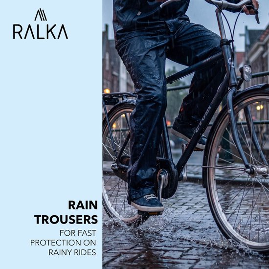 Iemand draagt een zwarte regenbroek tijdens het fietsen door een plas in de regen.