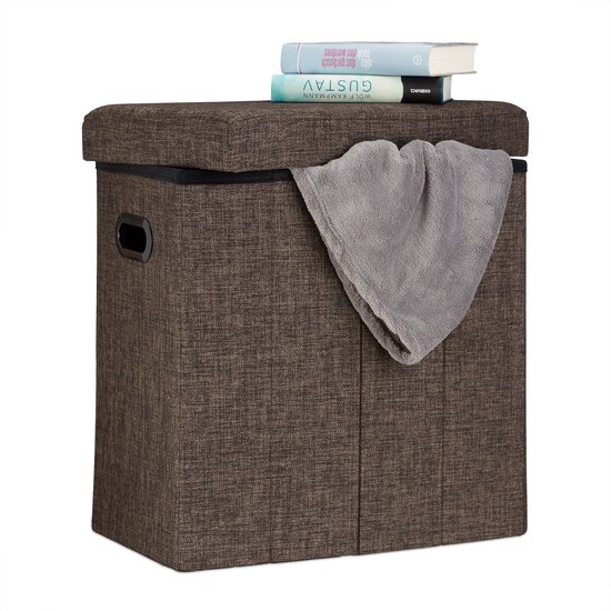 Bruine, rechthoekige stoffen opvouwbare poef met opbergruimte, boeken en een grijze doek erop.